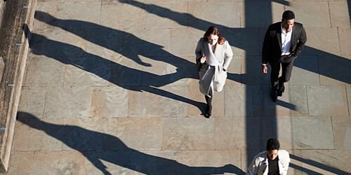 aerial view of people walking along the street, casting shadows